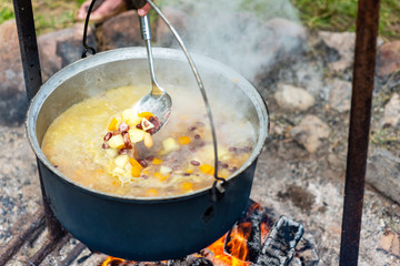 Cooking food in a pot on campfire. Summer camping concept.