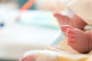 Obraz na płótnie Canvas The small tiny cute feet of the infant. Blurred light background