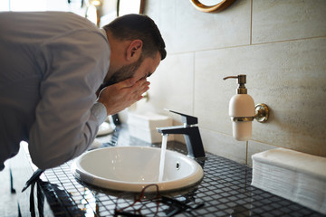 Young Well Dressed Man Bending Over Sink In Front Of Mirror