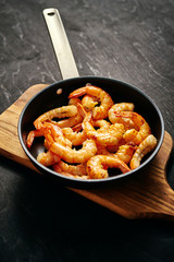 fresh delicious fried tiger prawns in a pan and wooden board