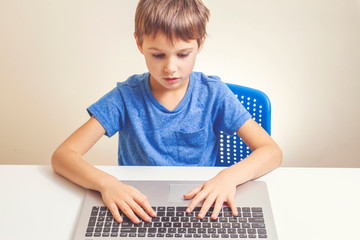 Concentrated boy typing on laptop computer