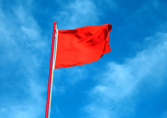 red flag waves in the sky and signals the rough sea