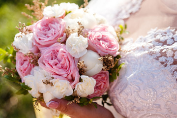 a delicate bouquet of white and pink roses in the hands of the bride