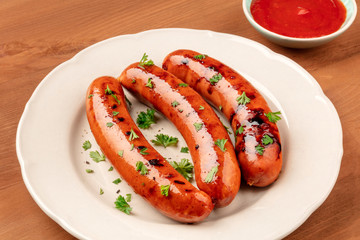 A photo of a plate of fried sausages and ketchup on a dark rustic wooden background with copy space