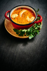 traditional Thai soup with shrimp and coconut milk in a red pot with parsley