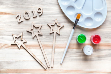 Do it yourself wooden stars and 2019 cut outs with paint and a brush on a wooden pine surface, new year 2019 craft concept