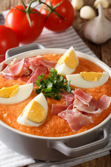 Fresh summer Antequera Porra soup of tomatoes, peppers and garlic served with boiled eggs and ham closeup in a pan. vertical