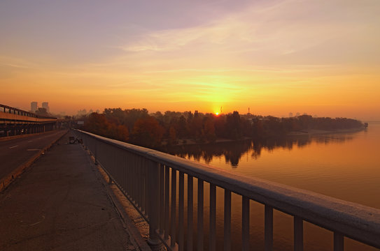 Wide angle landscape panorama of Dnipro River. Magnificent autumn sunrise in Kyiv. Foggy morning landscape. Beautiful city view with rising sun and fiery sky. Kyiv (Kiev), Ukraine