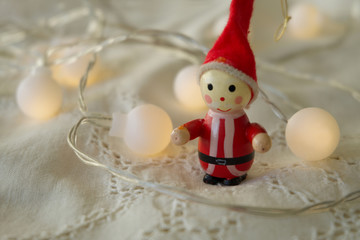 Little Santa Claus with warm Christmas lights on antique lace fabric 2