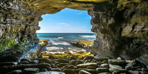 Rock cave on the sea with view of ocean and sky - obrazy, fototapety, plakaty