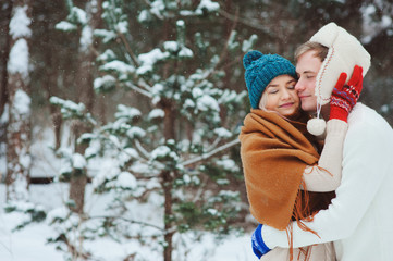 happy young loving couple walking in snowy winter forest, covered with snow, having fun and hug. Active winter vacations outdoor.