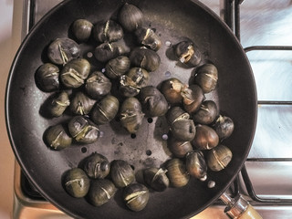 Cooking chestnuts on a pan by flames