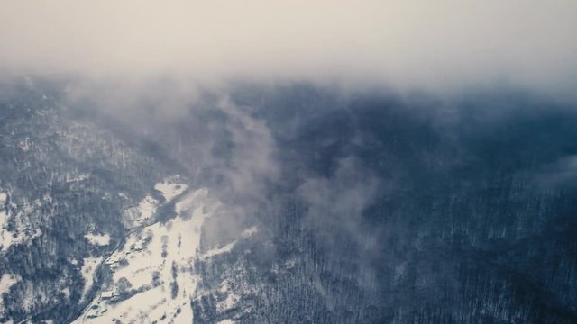 Aerial shot: Mountain village in fog from bird eae view