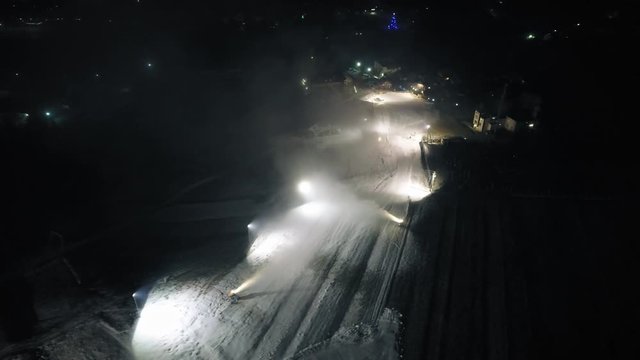 Aerial shot: The snow cannon's makes artificial snow at night. Winter sports