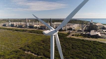 Drone shot behind wind turbine with aluminum smelter in background -  Filmed under our CASA ReOC UAV commercial license.