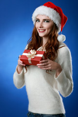 Happy woman wearing Santa hat holding gift box. Close up portrait with shoulders.