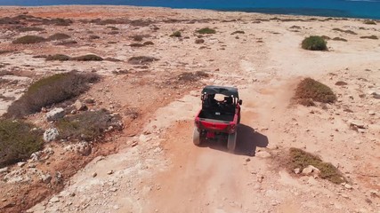A couple speed off across rocky terrain in a four wheeler while off road