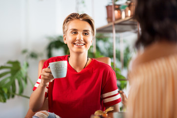 people, communication and friendship concept - female friends drinking coffee and talking at cafe