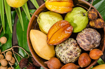 Assorted Thai tropical fruits on a dark wooden rustic background.