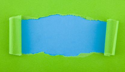 torn green paper isolated on blue background