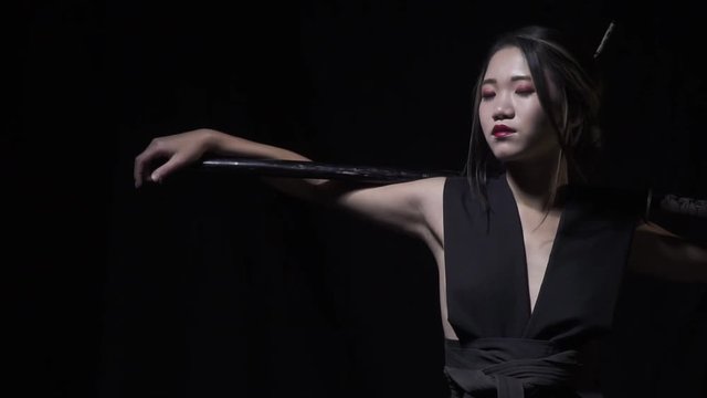 Elegant, dangerous asian woman with katana on her shoulders