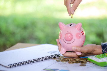 Woman hand putting coin into piggy bank. Saving money wealth and financial concept.