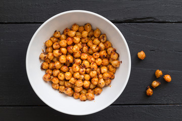 Chickpeas with olive oil and chili flakes - Spicy chickpeas in white bowl on black rustic background - top view photo