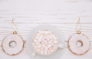 hot chocolate with marshmallow candy and Christmas decorations in the form of a donut on a white wooden background. Copy space