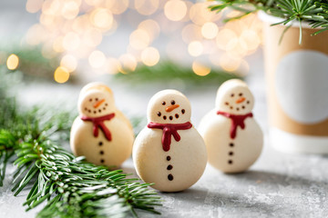 Variety of sweet macaroons. Cookie in the form of a snowman. Fir branches on a gray background. Merry Christmas card. New year mood