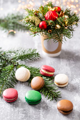 Variety of sweet macaroons. Fir branches on a gray background. Merry Christmas card. New year mood