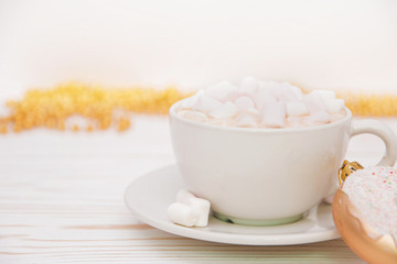 hot chocolate with marshmallow candy and Christmas decorations in the form of a donut on a white wooden background. Copy space