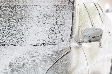 Detergent soap foam known as snow wash sprayed onto car
