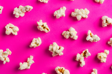 Scattered cooked popcorn on pink background. Сoncept of leisure