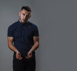Detention and arrest concept. A young man holds hands to put handcuffs on them. Studio shot on gray...