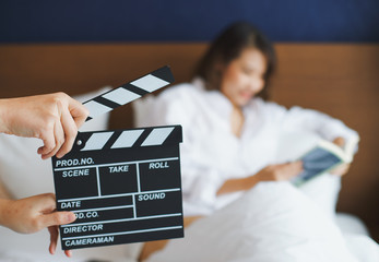 Close up hands holding clapperboard during the production of the film with asian woman reading a...