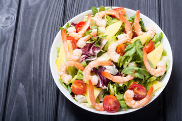 Mix of salad with shrimps , avocado and cherry tomatoes . Healthy food background