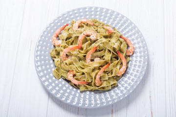 Pasta tagliatelle with sauce pesto and shrimps . Italian food background