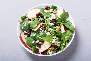Autumn spinach salad with apple , cheese , walnut and dried cranberry . Healthy vegetarian food