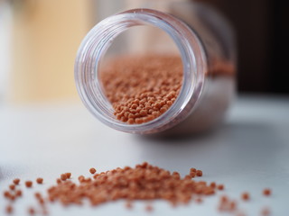 Fish feed Small pellets In a clear plastic bottle with a lid on a white background.