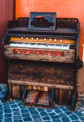 Fototapeta na wymiar Retro piano on the street with stones. Wooden design and old style ornaments