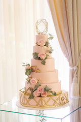 Beautiful wedding cake decorated with flowers. Pink color of cake. Powder rose