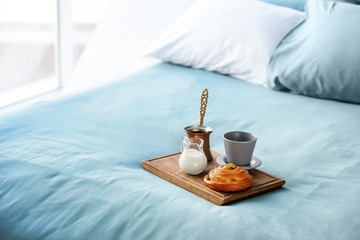 Wooden board with delicious breakfast on bed
