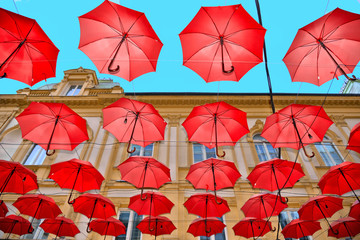 street decoration with colorful red umbrellas against blue sky between buildings on the street in old part of Belgrade, Serbia