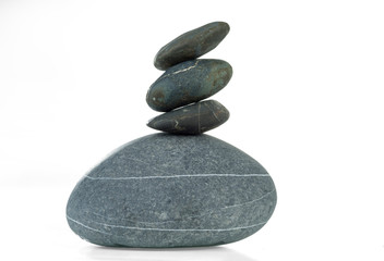 A pyramid of four stones in balance is isolated on a white background.