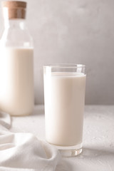 Glass and bottle of tasty milk on white table