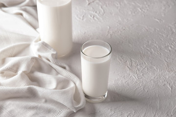 Glass and bottle of tasty milk on white table
