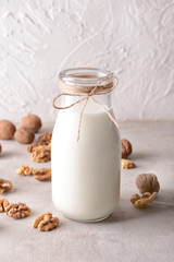 Bottle of tasty milk and walnuts on white table