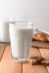 Glass of tasty milk and cookies on wooden table