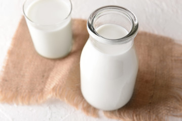 Obraz na płótnie Canvas Bottle and glass of tasty milk on light table
