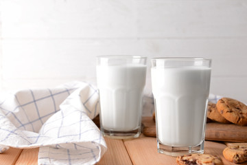 Glasses of tasty milk and cookies on wooden table